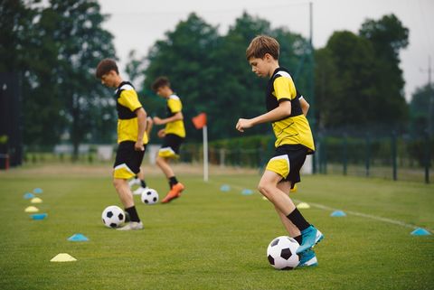 Jeugdvoetballers oefenen balcontrole met pionnen tijdens een training